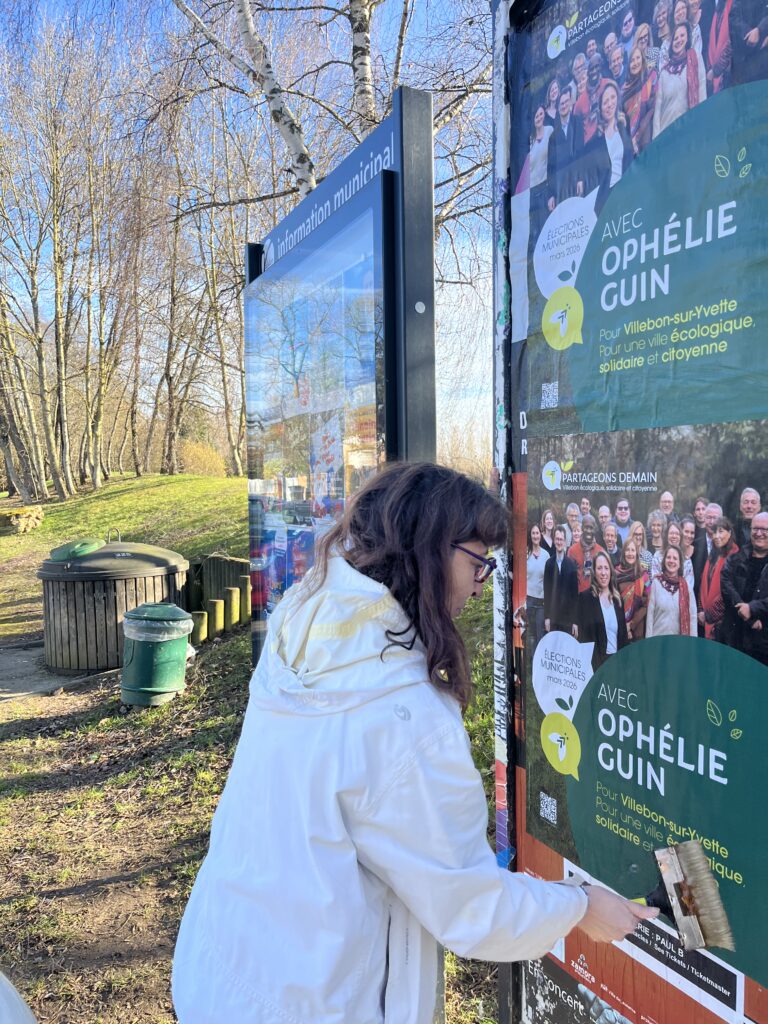 Image représentant une personne de la liste Partageons Demain en train de coller l'affiche de la campagne pour les municipales